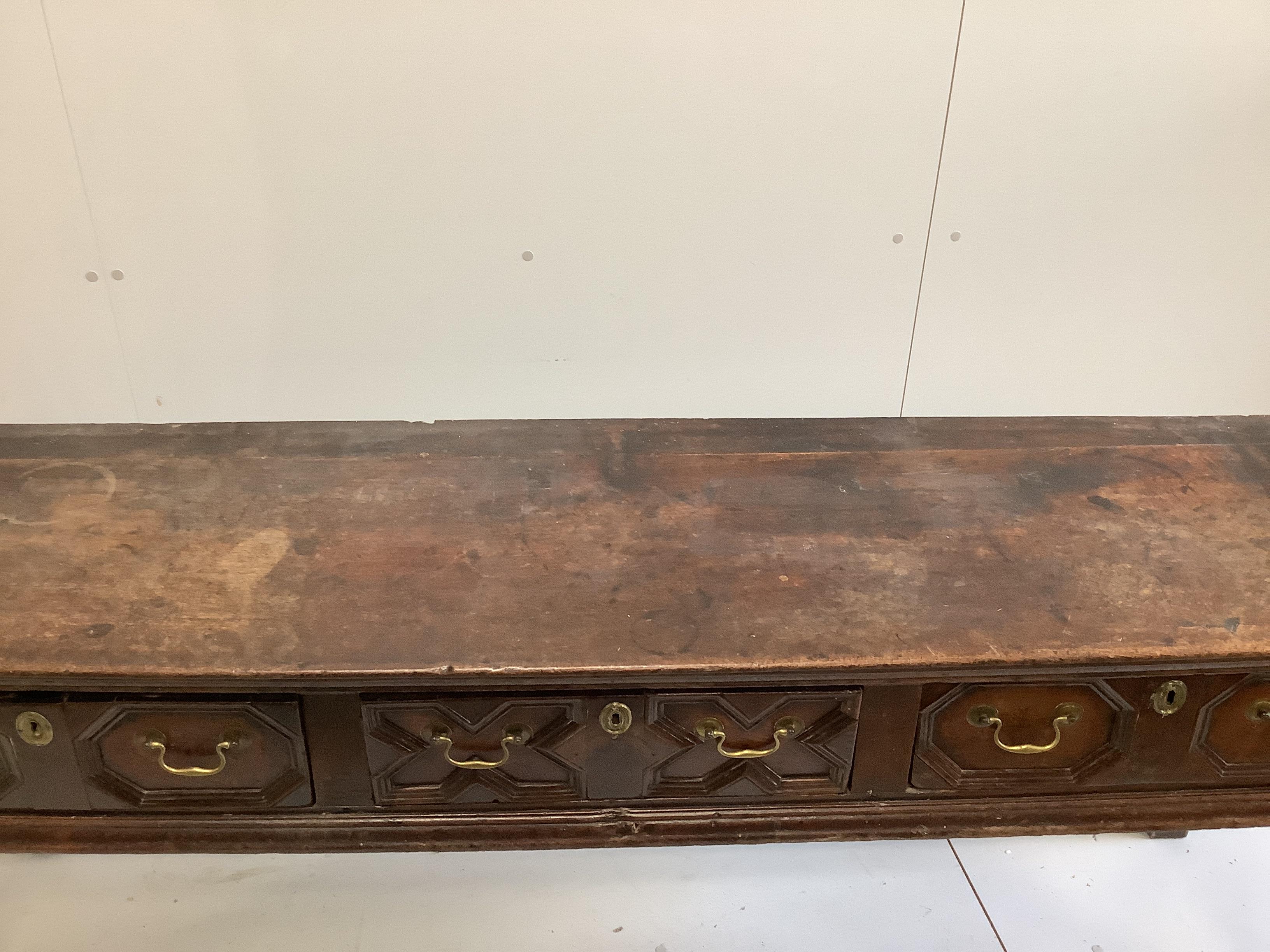 An 18th century oak low dresser fitted with geometric moulded drawers and brass handled over turned supports, length 193cm, width 49cm, height 74cm